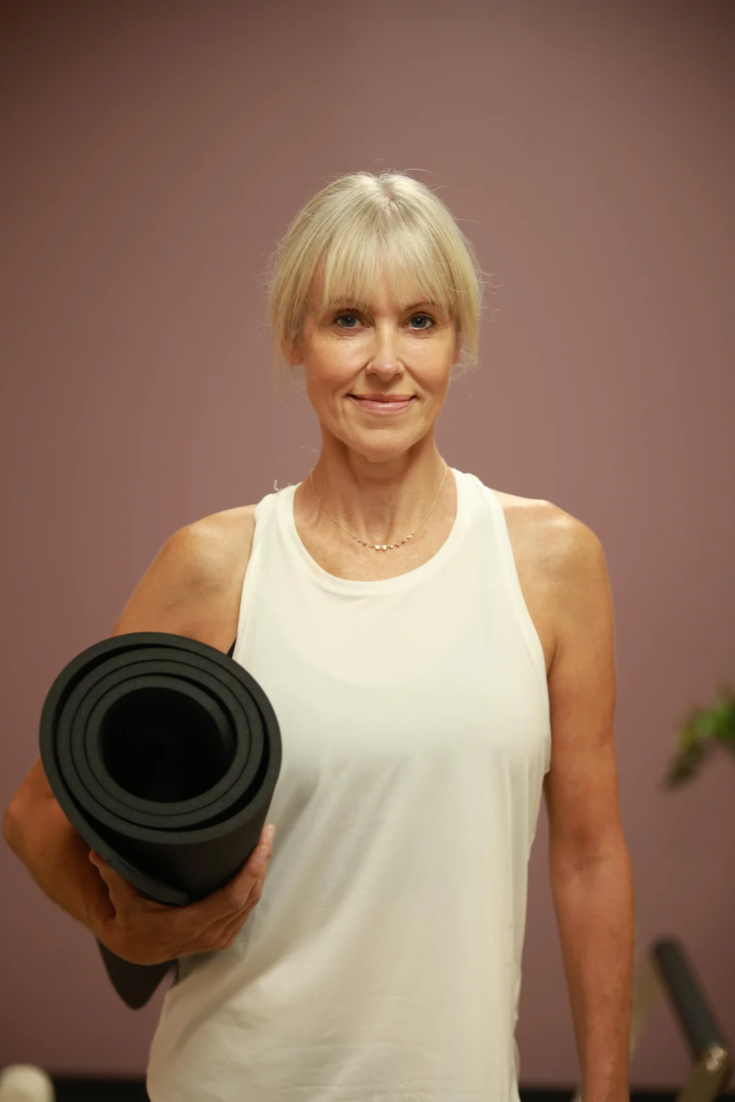 Studio portrait with a rolled Pilates mat